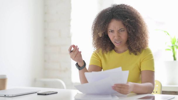 Young African Woman Upset while Reading Documents in Office - Foto, Bild