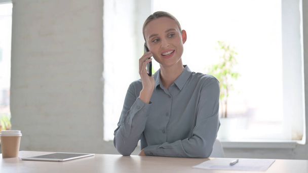 młoda kobieta rozmawia przez telefon w biurze - Zdjęcie, obraz