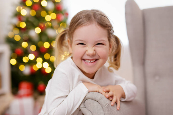 Close up portrait of a small girl near christmas tree - Photo, Image