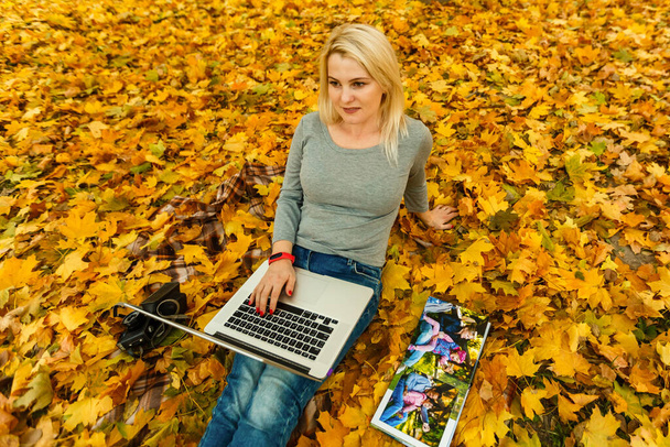 woman with laptop and photo book in autumn park. - Φωτογραφία, εικόνα