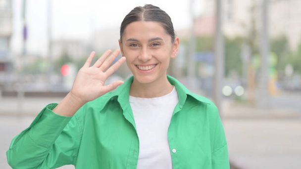 Welcoming Young Woman Waving Hand for Hello Outdoor - Foto, imagen