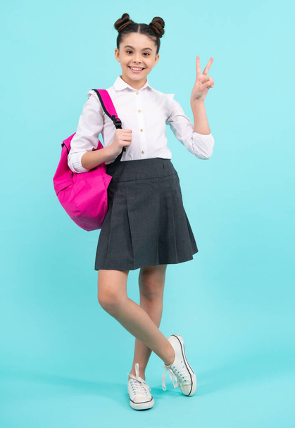 Okul üniformalı okul çantalı kız. Öğrenci, genç öğrenci sırt çantasını mavi izole edilmiş arka planda tutuyor. Mutlu ergen, pozitif ve gülümseyen genç kız duyguları - Fotoğraf, Görsel