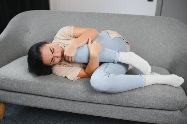 Young woman suffering from menstrual cramps at home. Gynecology. - Foto, Bild