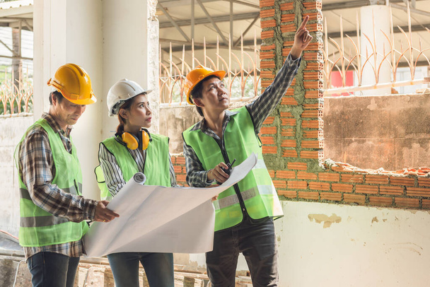 Zespół azjatyckich inżynierów budownictwa mężczyzna i kobieta szukają planu i w punkcie i omówić renowacji starego domu, aby być nowym domem, do nieruchomości i koncepcji renowacji. - Zdjęcie, obraz