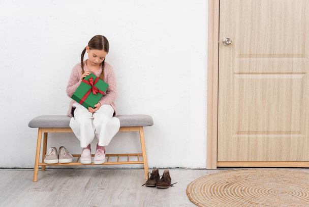 Preteen Kind hält Geschenk in der Nähe der Tür zu Hause  - Foto, Bild
