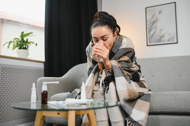Sick Woman.Flu.Woman Caught Cold. Sneezing into Tissue. Headache. Virus .Medicines. Sick woman with a headache sitting on a sofa - Foto, Imagem