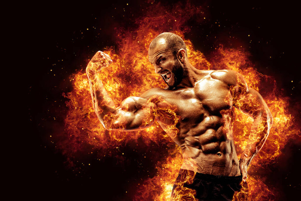 Bodybuilder posing on the fire flames background. High quality photo - Foto, Bild