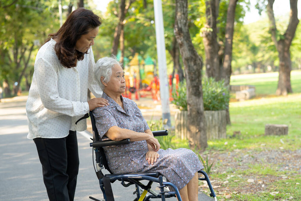 Pečovatel pomoc a péče Asijské starší nebo starší stařena pacient sedí a šťastný na invalidním vozíku v parku, zdravé silné lékařské koncepce. - Fotografie, Obrázek