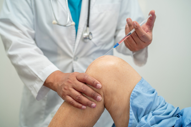 Азиатский врач вводит богатую плазму гиалуроновой кислоты в колено пожилой женщины, чтобы ходить без боли. - Фото, изображение