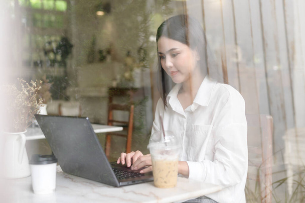 A young woman working with laptop computer in cafe  - 写真・画像