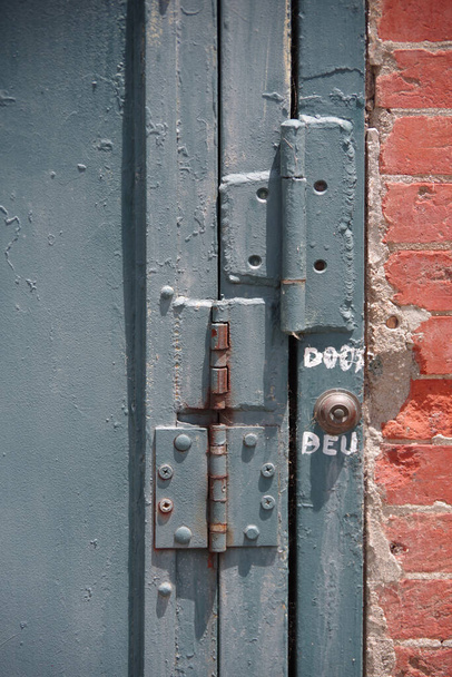 Частковий вигляд старих синіх залізних дверей з трьома петлями і дзвіночком дверей
 - Фото, зображення