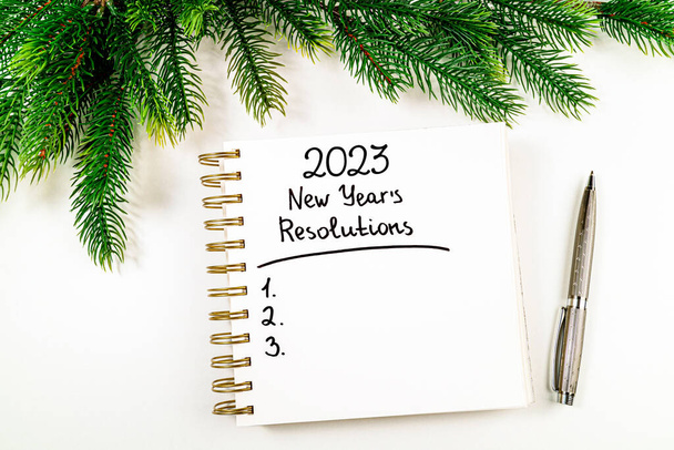 Obiettivi di Capodanno 2023 sulla scrivania. 2023 elenco delle risoluzioni con taccuino, tazza di caffè e albero di Natale sul tavolo bianco. Risoluzioni, piano, obiettivi, azione, checklist, idea. Nuovo anno 2023 modello, copia spac - Foto, immagini