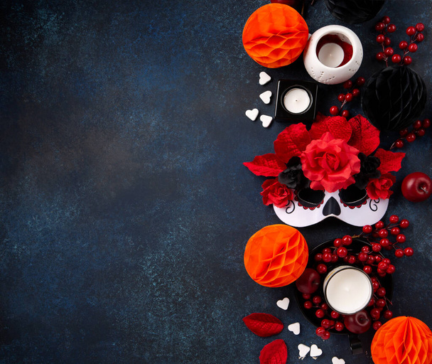 Dia de los Muertos, mexikanischer Feiertag der Toten und Halloween. Weiße Karnevalsmaske, Kerzen, Blumen und mexikanische Objekte auf dunkelblauem Hintergrund. Konzeptplakat, Banner, Festkarte. - Foto, Bild