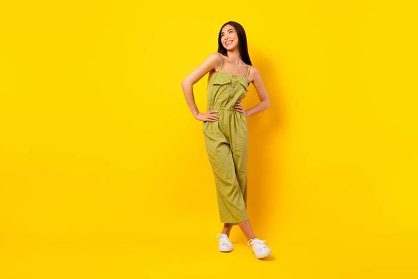 Full size portrait of cute positive filipino lady put hands waist look empty space isolated on yellow color background. - Zdjęcie, obraz