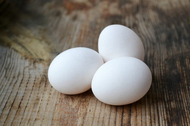 Три белых яйца на деревянном столе
 - Фото, изображение