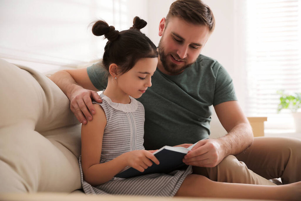 Little girl with father reading fairy tale in living room - Foto, immagini