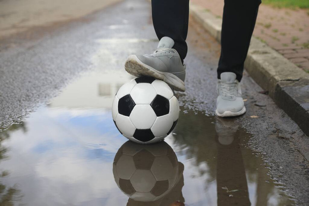 Man with soccer ball near puddle outdoors, closeup - 写真・画像