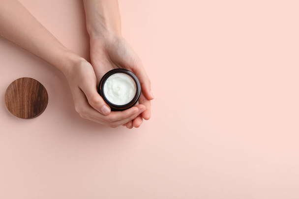 Woman holding jar of hand cream on pink background, top view. Space for text - Φωτογραφία, εικόνα