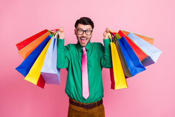 Photo of shocked funky man dressed green shirt eyewear holding colorful shoppers isolated pink color background. - Φωτογραφία, εικόνα