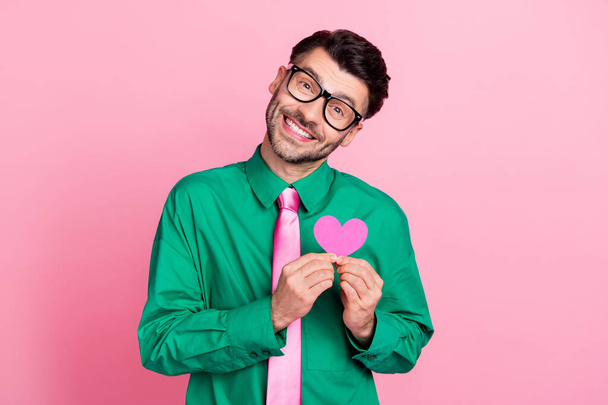 Photo of funky dreamy man dressed green shirt eyewear smiling holding small heart isolated pink color background. - Foto, imagen