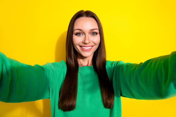 Photo selfie smiling cute young lady attractive nice beaming blogger showing new green pullover isolated on yellow color background. - Photo, image