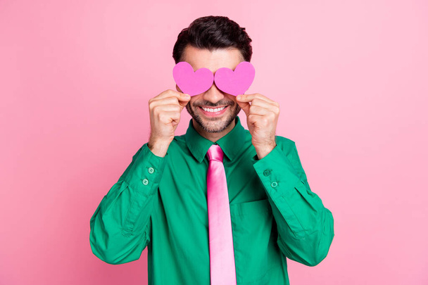Photo of pretty charming guy wear green shirt two little hearts cover eyes isolated pink color background. - Foto, Bild
