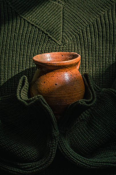 Immagine verticale di un maglione verde militare lavorato a maglia con una tazza di ceramica - Foto, immagini