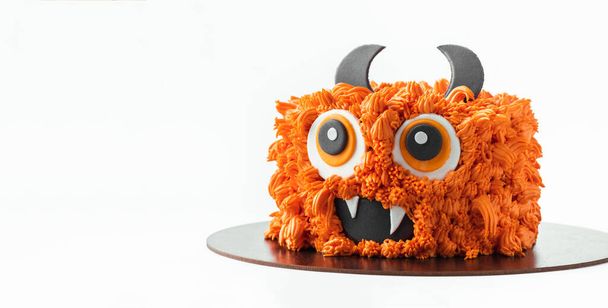 gâteau thème monstre sur le fond blanc. Gâteau d'Halloween avec glaçage au fromage à la crème moelleux orange isolé sur blanc - Photo, image