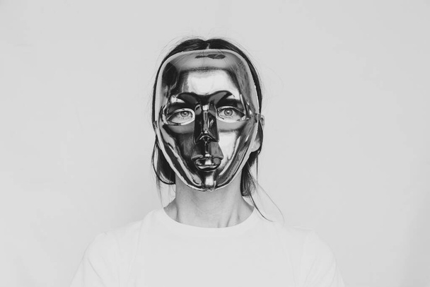 Menina em uma máscara de plástico sem rosto em um fundo branco foto preto e branco, anonimato, mistério - Foto, Imagem