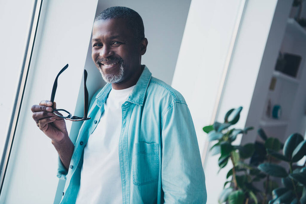 Foto di ottimista uomo anziano tenere gli occhiali stare vicino alla finestra sentire l'ispirazione su start-up nel posto di lavoro moderno. - Foto, immagini