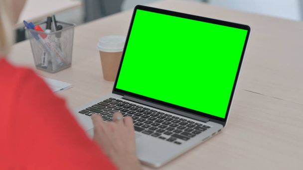 Mujer joven usando el ordenador portátil con la pantalla dominante verde del croma - Foto, Imagen