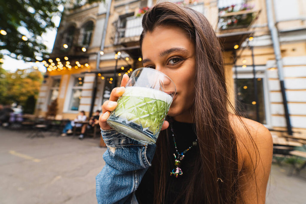 Femme tenant tasse en verre de smoothie savoureux et boire - Photo, image