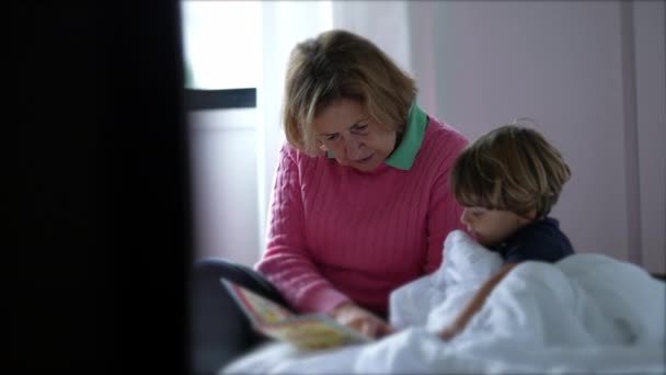 Abuela leyendo un libro a su nieto. El abuelo cándido cuenta una historia a la hora de acostarse a un niño pequeño - Metraje, vídeo