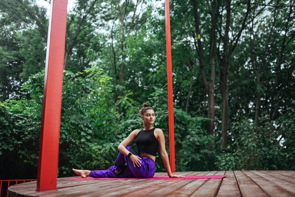 Une jeune femme dans le yoga dans la cour sur la véranda - Photo, image