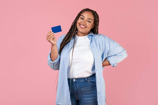 Cheerful African American Obese Woman Holding Credit Card Posing Standing Over Pink Studio Background, Smiling To Camera. Finances, Great Bank Offer Concept - Fotografie, Obrázek