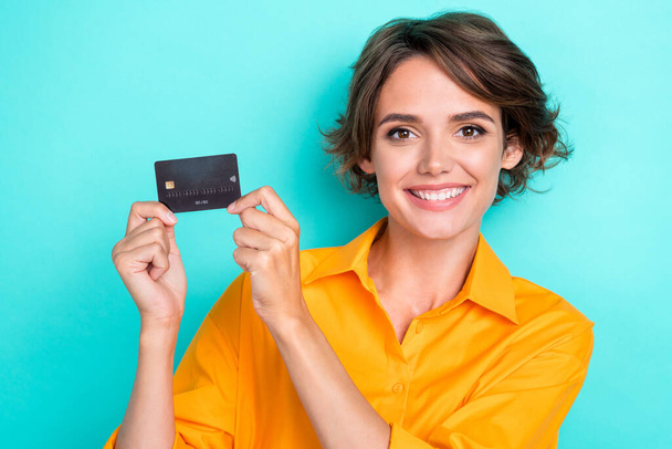 Closeup photo of young adorable pretty nice girlish lady hold debit card can get salary right now wireless payment isolated on cyan color background. - Foto, afbeelding