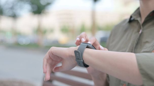 Крупним планом молода жінка використовує Smartwatch на відкритому повітрі
 - Фото, зображення