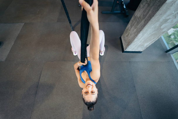 Mujer joven trepa una cuerda en el gimnasio Concepto de deporte. - Foto, imagen