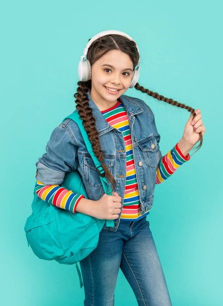 Happy teenager blue background. Girl teenager back to school. Teenager listening to music in headphones. Non-formal education. - Photo, Image