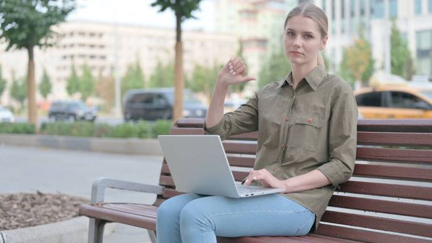 Великі пальці вниз молодою жінкою з ноутбуком сидить на лавці
 - Фото, зображення