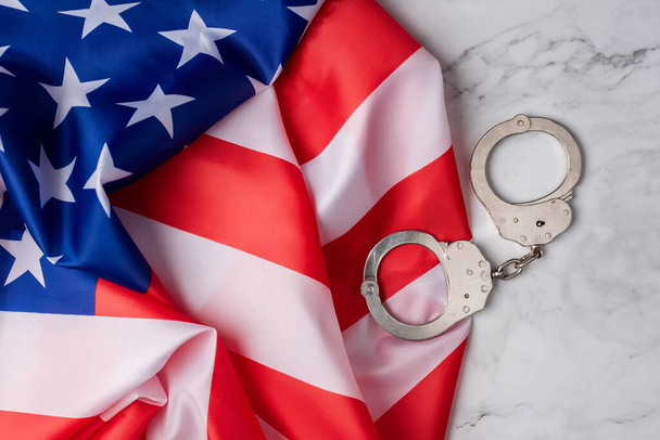 Wallpaper з прапором об'єднаних держав поруч з наручниками на білій мармуровій базі. Американська судова система - Фото, зображення