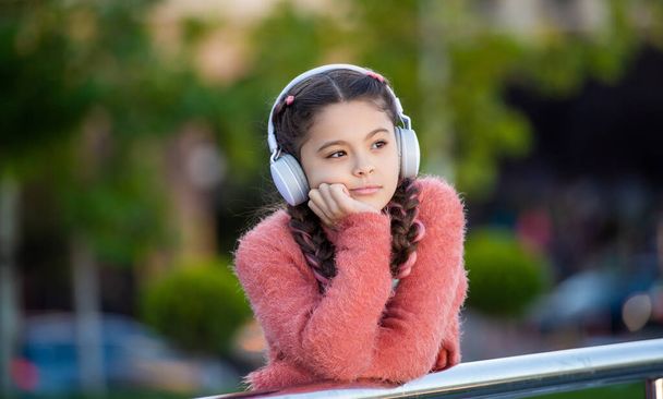 Teen girl thinking leaning on railing, thinking. Thoughtful teenager thinking while listening to music outdoors. - Fotoğraf, Görsel
