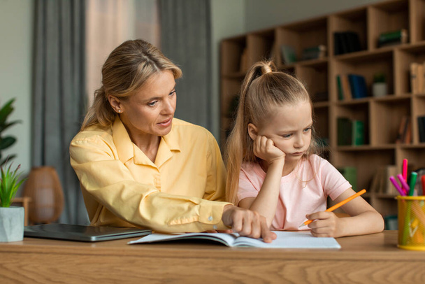 Строга мати, яка навчається з маленькою школяркою донькою, читає лекції для поганих оцінок, авторитетна мама, яка виховує маленьку доньку, не мотивує робити домашнє завдання
 - Фото, зображення