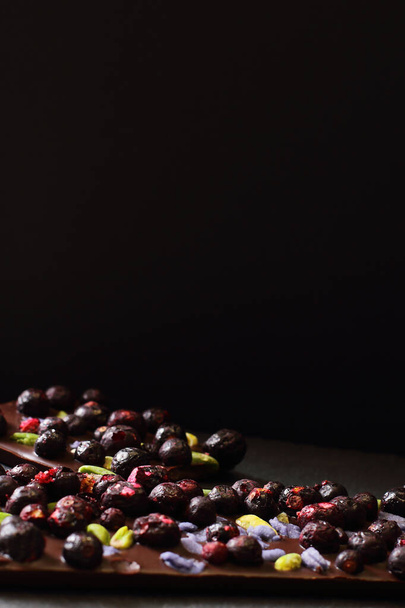 Chocolate dark bar with dried fruits on black background - Foto, Bild
