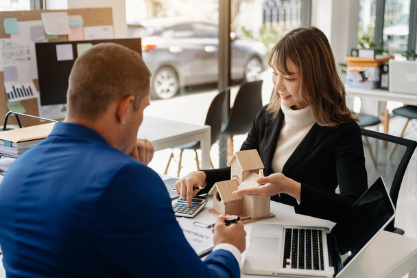 Real estate broker agent presenting and consult to customer to decision making sign insurance form agreement, home model, concerning mortgage loan offer in modern office - 写真・画像