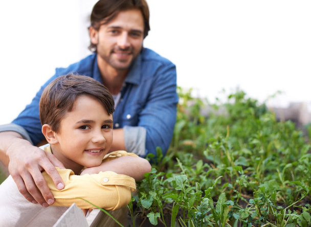 Tending to the plants together. a father and son standing beside their herb garden - Foto, Imagen