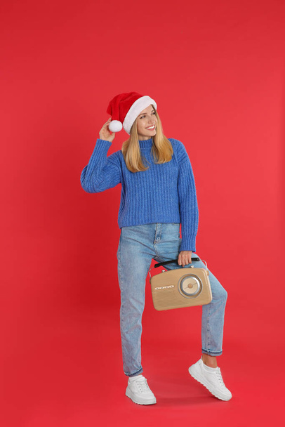 Happy woman with vintage radio on red background. Christmas music - Foto, afbeelding