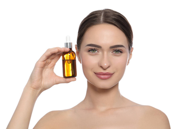Young woman with bottle of essential oil on white background - Фото, изображение