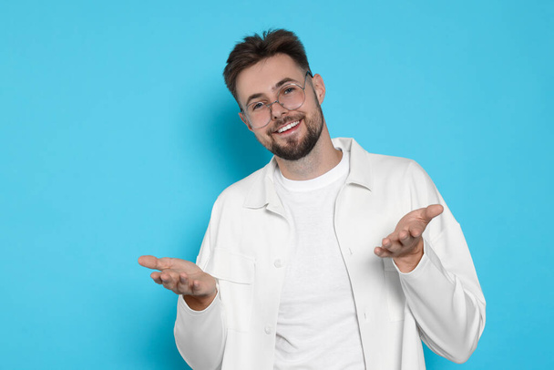 Handsome man in white jacket on light blue background - Foto, immagini