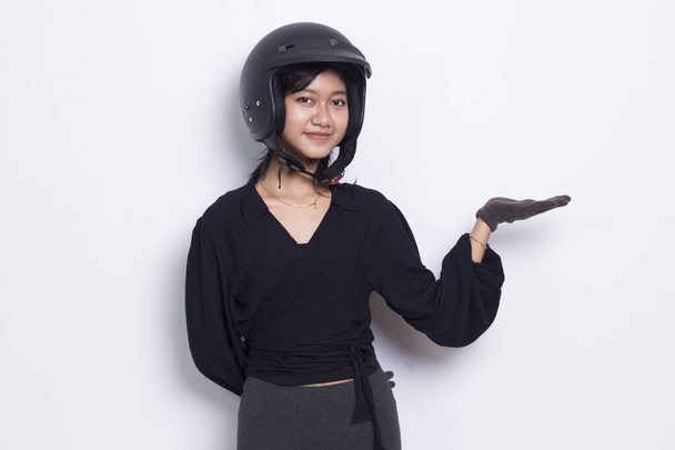 красивая азиатская женщина в мотоциклетном шлеме указывая пальцами в разные стороны, изолированные на белом фоне - Фото, изображение